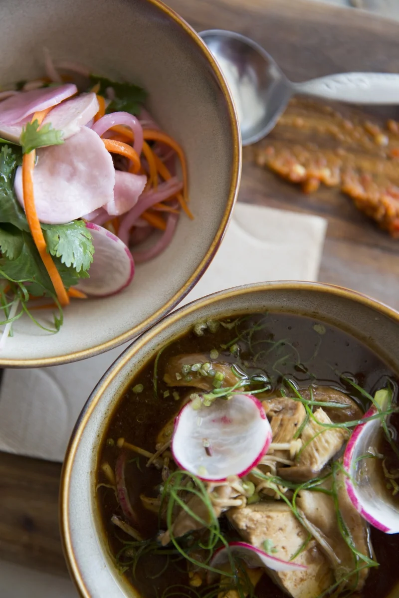 "The ever changing vegan bowl" Soy mushroom broth with pickles, tofu and noodles.